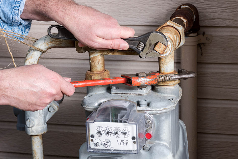 Technician working on a home gas meter with tools